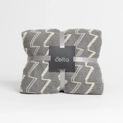Manta Zigzag modelo Gray doblada, envuelta con cinta gris y etiqueta Celta